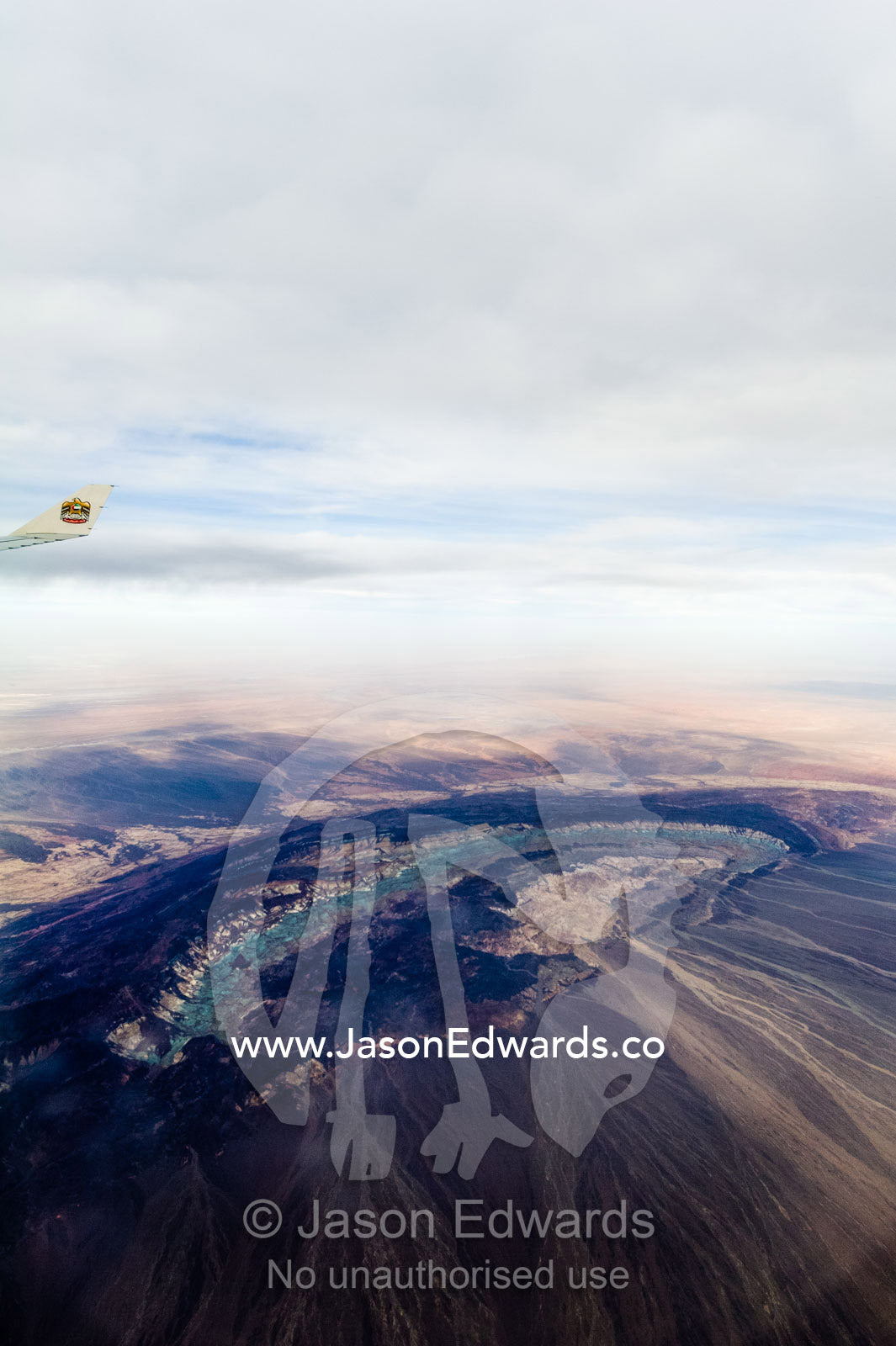A plane wing passes above the black volcanic slopes of a volcano caldera. Islamic Republic of Iran.