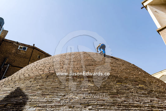 Children climb the steep sides of an ancient handmade brick cistern containing town water. Kashan, Isfahan Province, Islamic Republic of Iran.