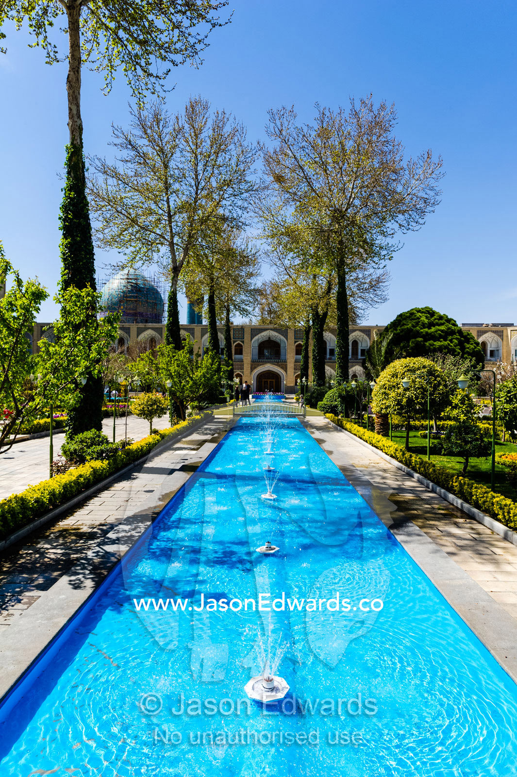 An ornamental pond with fountains and traditional garden in a caravanserai converted into a boutique hotel. The Abbasi Hotel, Isfahan, Isfahan Province, Islamic Republic of Iran.