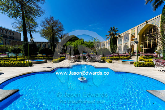 An ornamental pond with fountains and traditional garden in a caravanserai converted into a boutique hotel. The Abbasi Hotel, Isfahan, Isfahan Province, Islamic Republic of Iran.