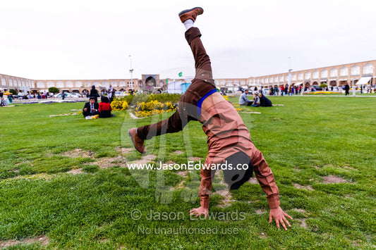 A boy doing cartwheels on the grass whilst on the New Year holiday. Naqsh-e Jahan Square, Isfahan, Isfahan Province, Islamic Republic of Iran.