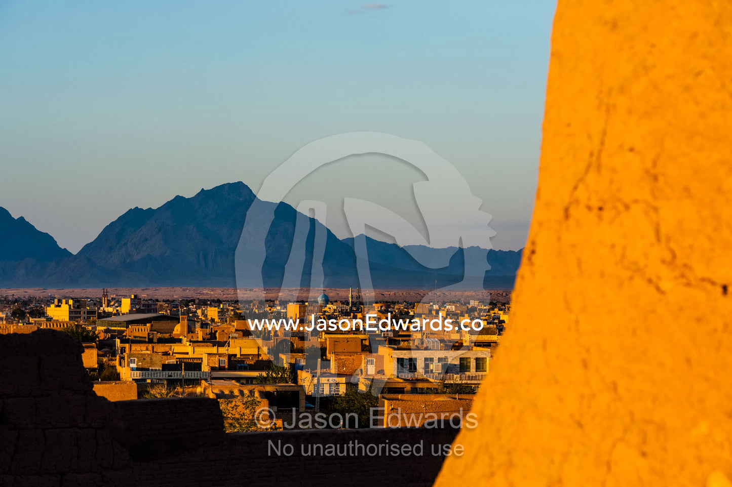 Sunset warms the walls of an ancient mud brick fortress overlooking the desert plain. Narin Castle, Meybod, Meybod County, Yazd Province, Islamic Republic of Iran.
