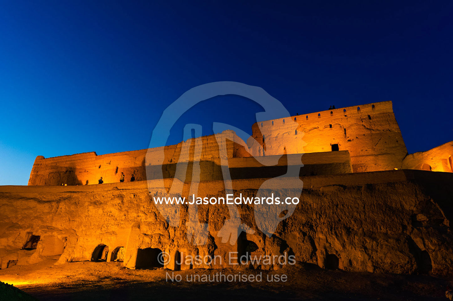 The imposing walls of an ancient mud brick fortress rising into the desert sky at night. Narin Castle, Meybod, Meybod County, Yazd Province, Islamic Republic of Iran.