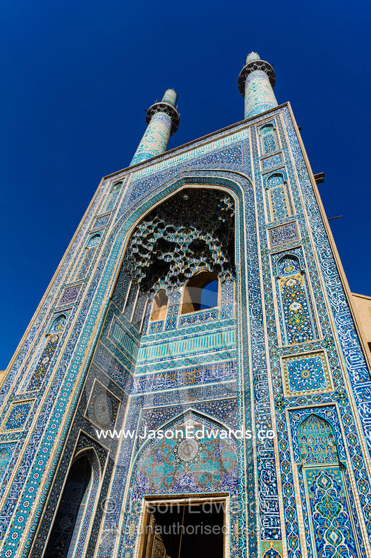 The towering blue tiled minarets above the vaulted iwan of the Jame Mosque rise into a clear blue sky. Jame Mosque of Yazd, Yazd, Yazd Province, Islamic Republic of Iran.
