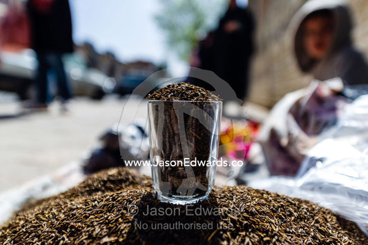 A glass used to measure caraway seeds for sale on a sidewalk. Yazd, Yazd Province, Islamic Republic of Iran.