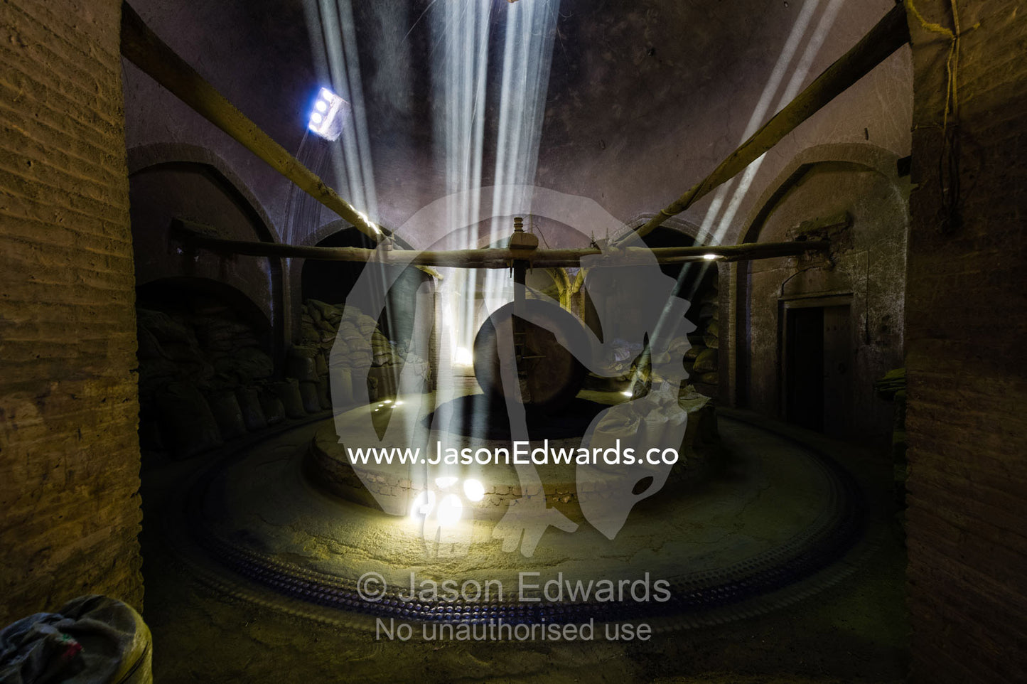 Sunrays light a giant stone wheel grinding henna seeds into powder in an ancient henna mill. Yazd, Yazd Province, Islamic Republic of Iran.