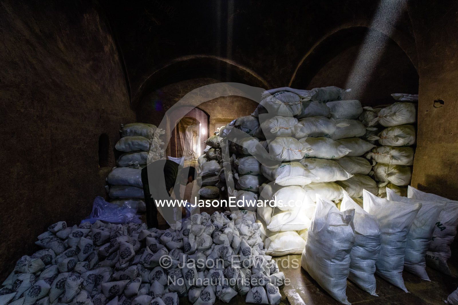 A labourer fills bags with henna for sale in an ancient henna mill. Yazd, Yazd Province, Islamic Republic of Iran.