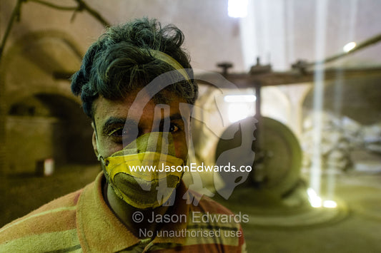 The exhausted face of a labourer wearing a dust mask working in an ancient henna mill. Yazd, Yazd Province, Islamic Republic of Iran.