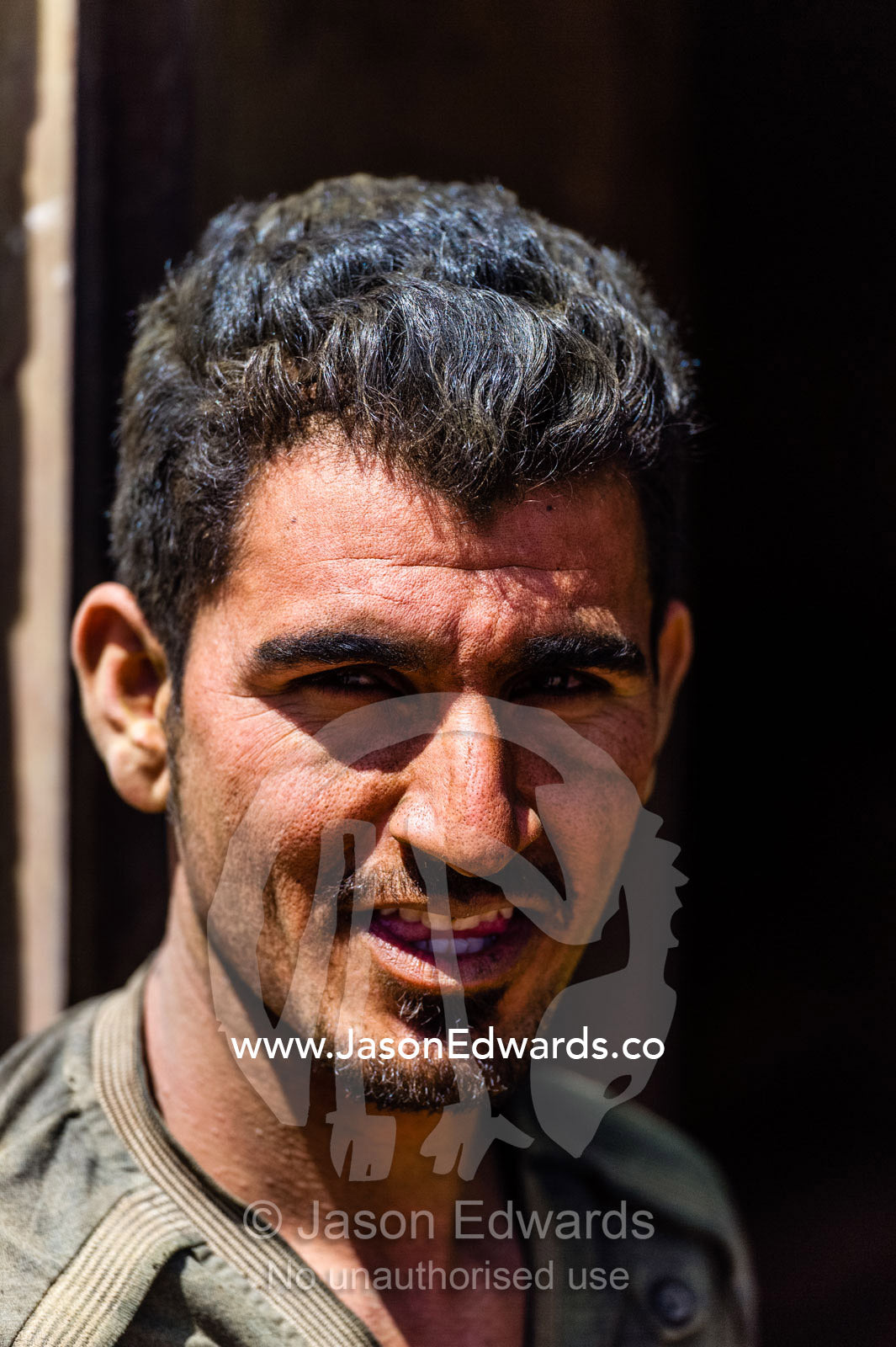 A smiling labourer takes a rest break from working in a henna mill. Yazd, Yazd Province, Islamic Republic of Iran.