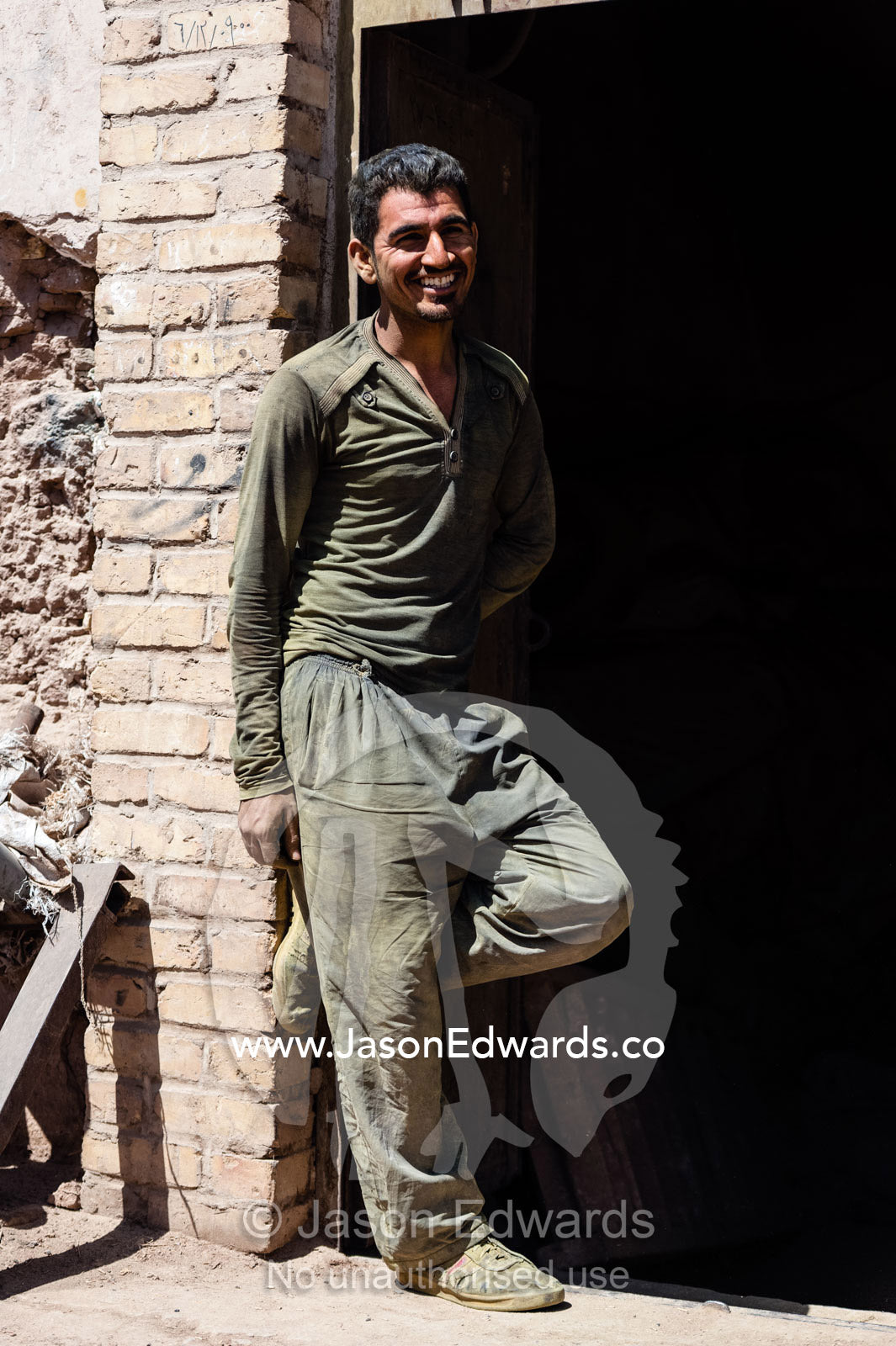 A smiling labourer takes a rest break from working in a henna mill. Yazd, Yazd Province, Islamic Republic of Iran.