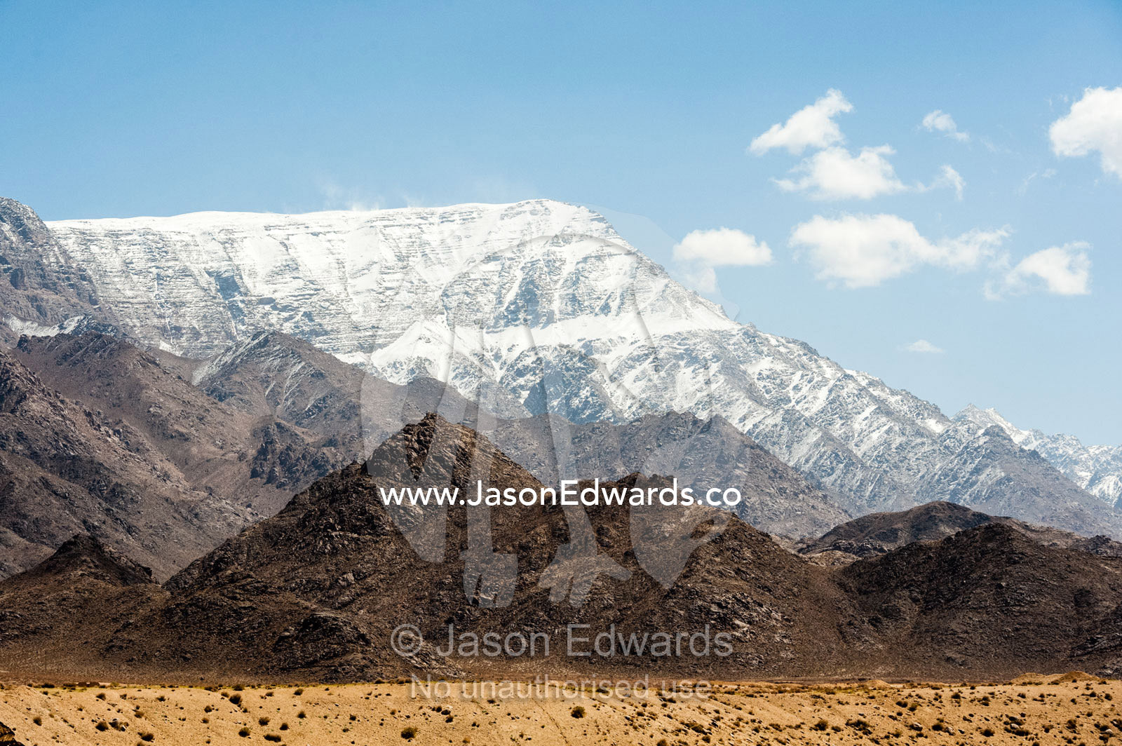 Snow-capped mountain peaks rise above the desert plain. Shir Kuh Mountain, Yazd, Yazd Province, Islamic Republic of Iran.
