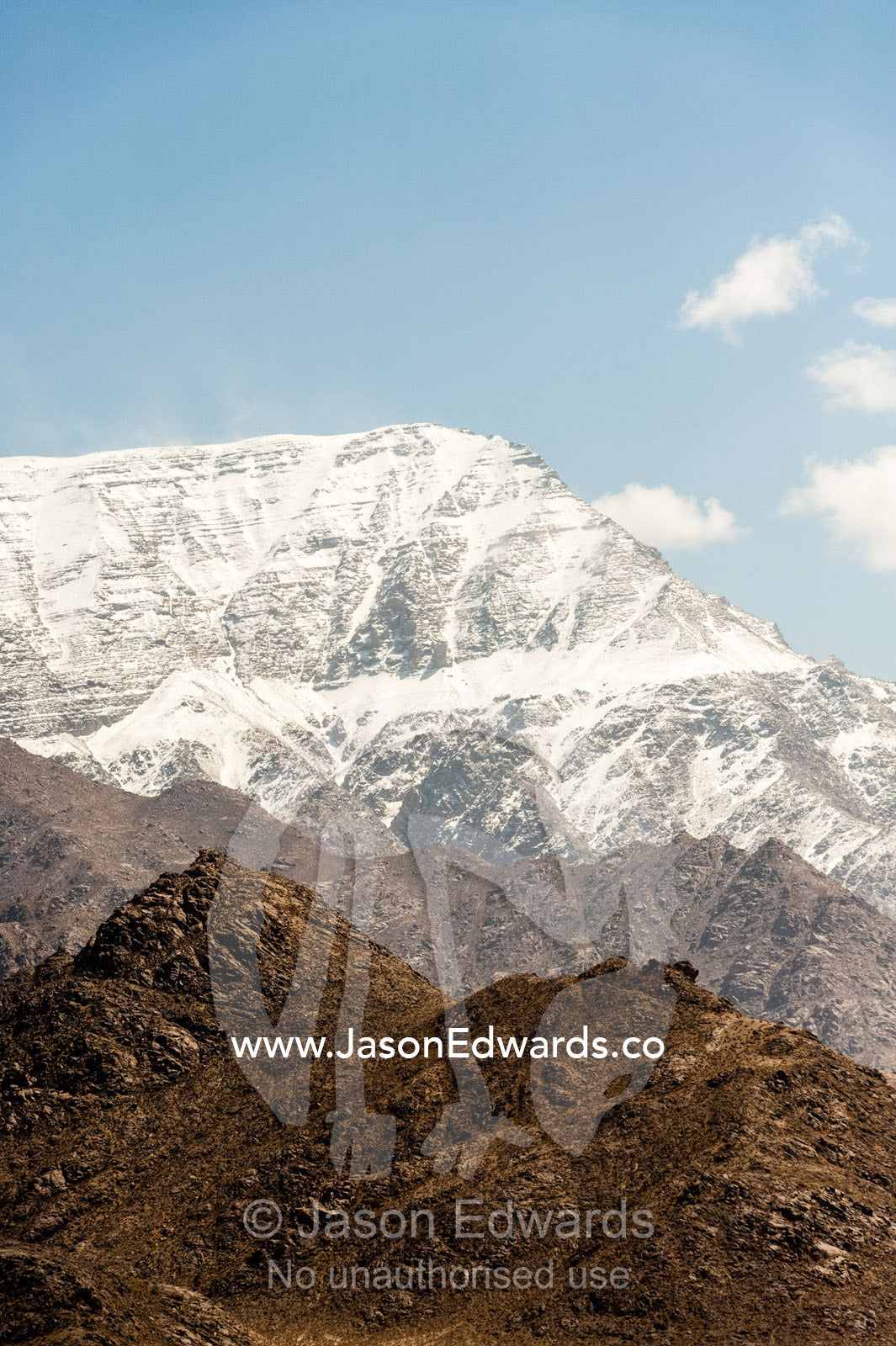 Snow-capped mountain peaks rise above the desert plain. Shir Kuh Mountain, Yazd, Yazd Province, Islamic Republic of Iran.