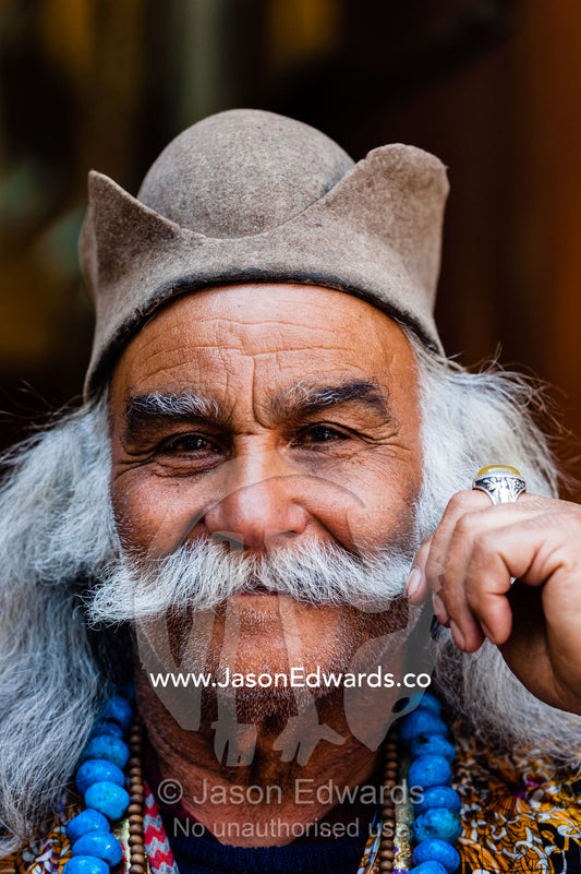 A man dressed in traditional nomad clothing twirls his moustache. Vakil Bazaar, Shiraz, Islamic Republic of Iran.