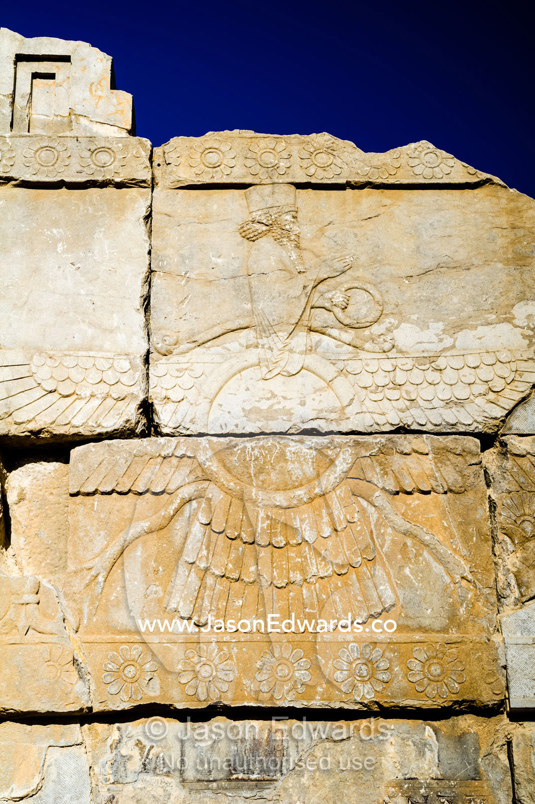 A symbol of the winged discs of Fravahr carved into a stone wall. Persepolis, Shiraz, Fars Province, Islamic Republic of Iran.