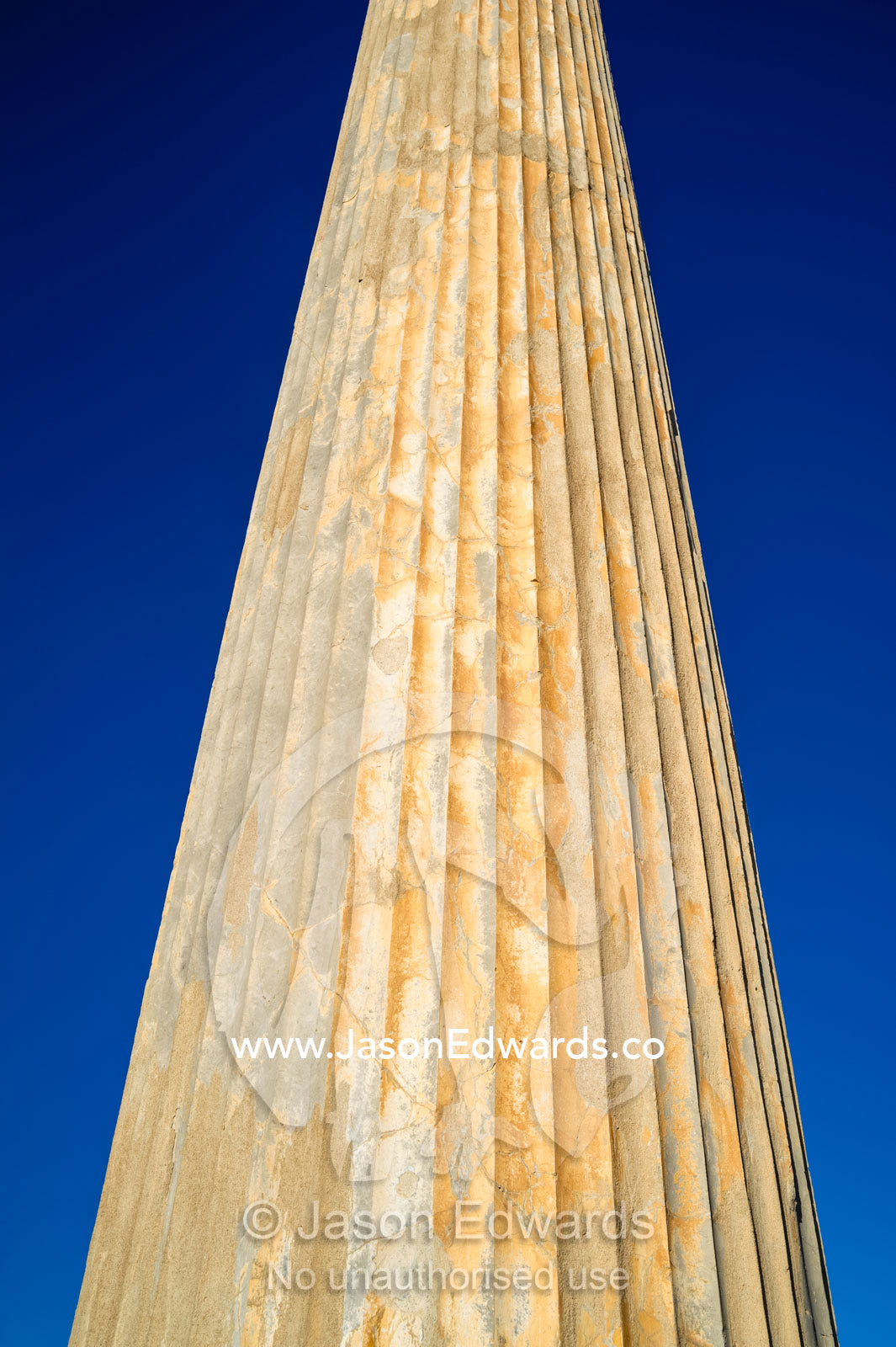 The towering stone columns of the Apandana Palace rising into a clear blue sky. Persepolis, Shiraz, Fars Province, Islamic Republic of Iran.