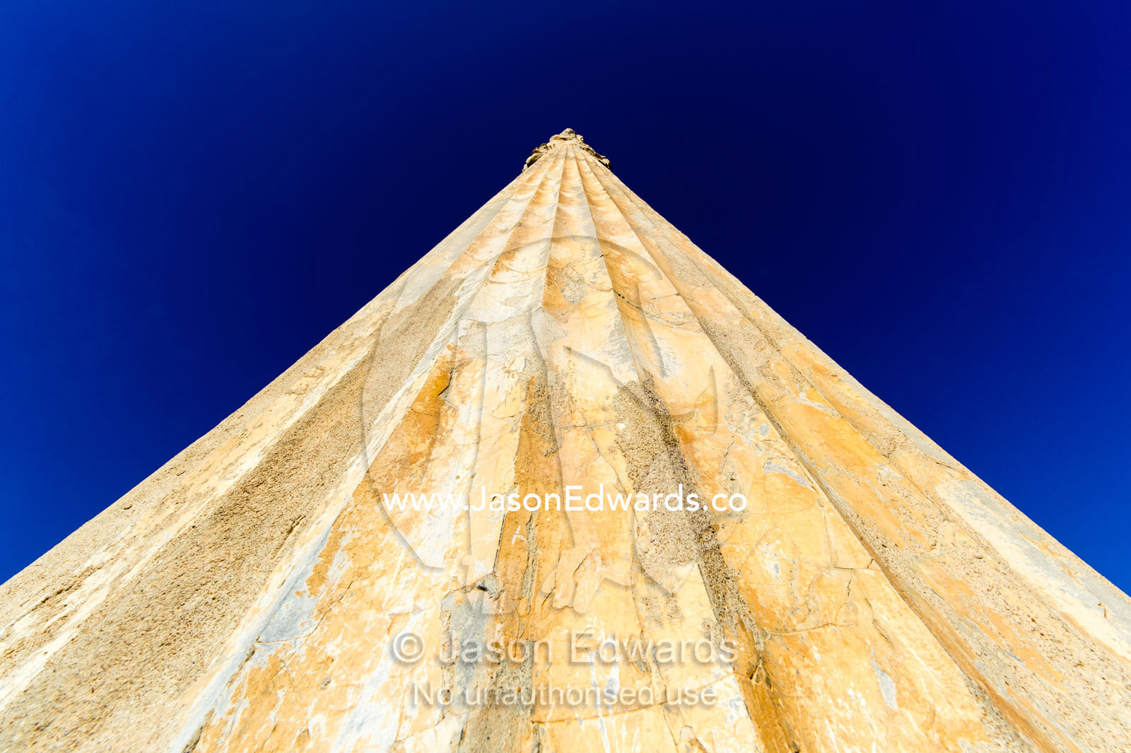 A low angle view of the towering stone columns of the Apandana Palace rising into a clear blue sky. Persepolis, Shiraz, Fars Province, Islamic Republic of Iran.