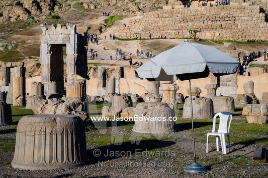 A security guard's plastic chair and umbrella among the ancient ruins of Persepolis. Persepolis, Shiraz, Fars Province, Islamic Republic of Iran.