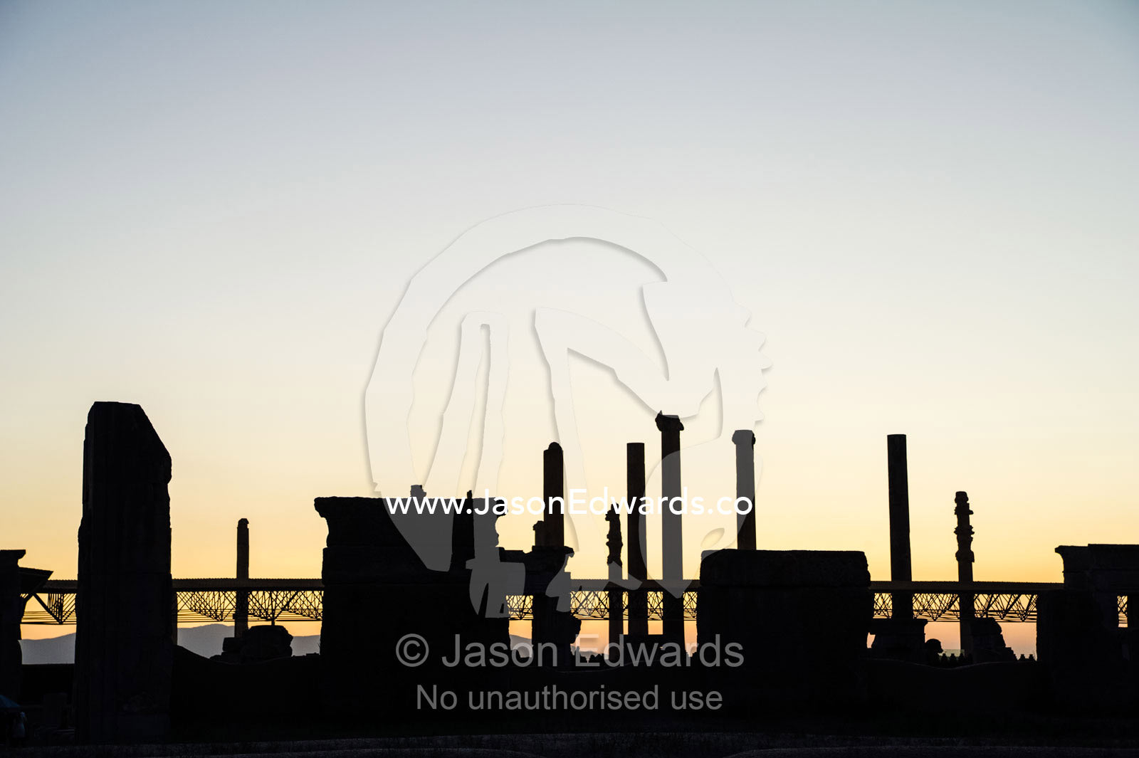 The ancient ruins of Persepolis silhouette on the horizon at sunset. Persepolis, Shiraz, Fars Province, Islamic Republic of Iran.