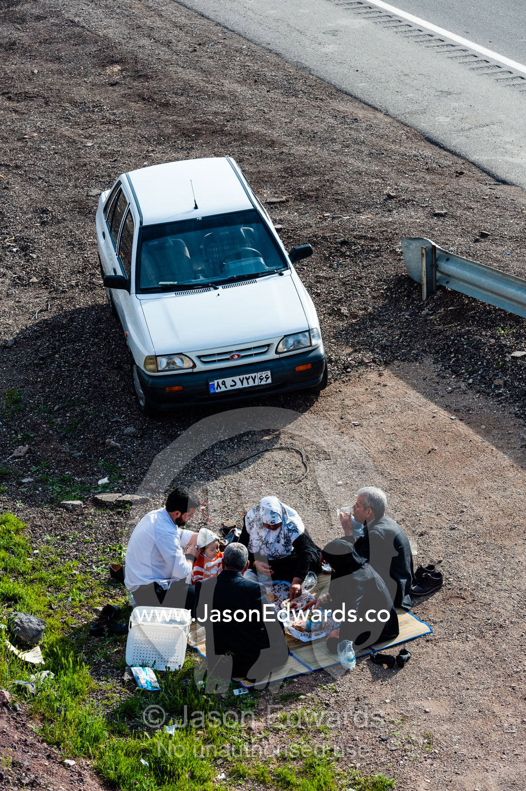 A family of Bedouins prepare a meal beside a highway in the desert. Qom Province, Islamic Republic of Iran.