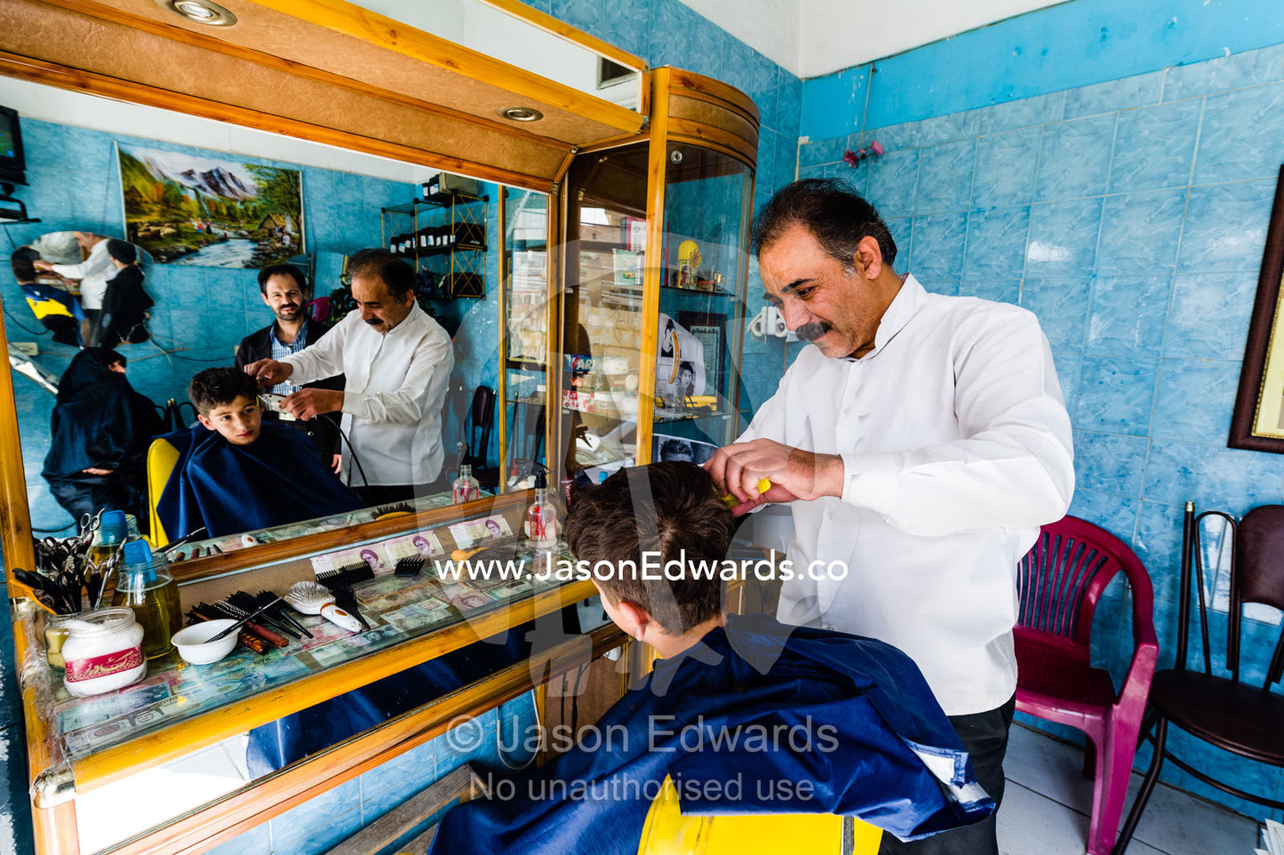 A barber cuts a teenage boys hair in a barber shop. Qom, Qom Province, Islamic Republic of Iran.