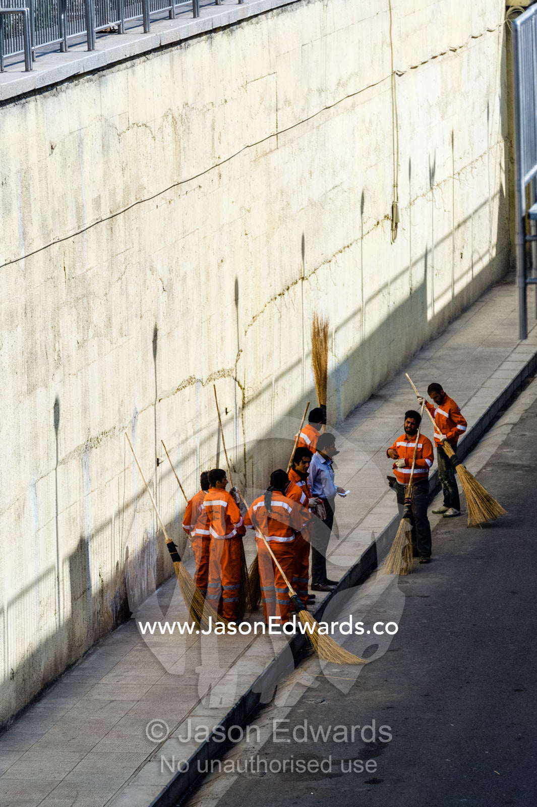 Street cleaners rest in the shade with their straw brooms. Qom, Qom Province, Islamic Republic of Iran.