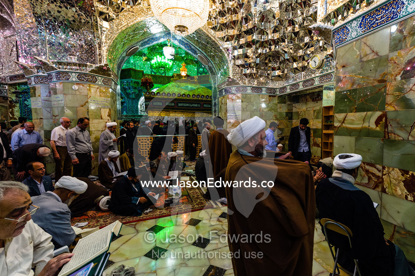 Men at prayer beneath the magnificent mirrored ceiling and chandelier of the Holy shrine of Hazrat Masuma. Fatima Masumeh Shrine, Qom, Qom Province, Islamic Republic of Iran.