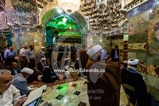 Men at prayer beneath the magnificent mirrored ceiling and chandelier of the Holy shrine of Hazrat Masuma. Fatima Masumeh Shrine, Qom, Qom Province, Islamic Republic of Iran.