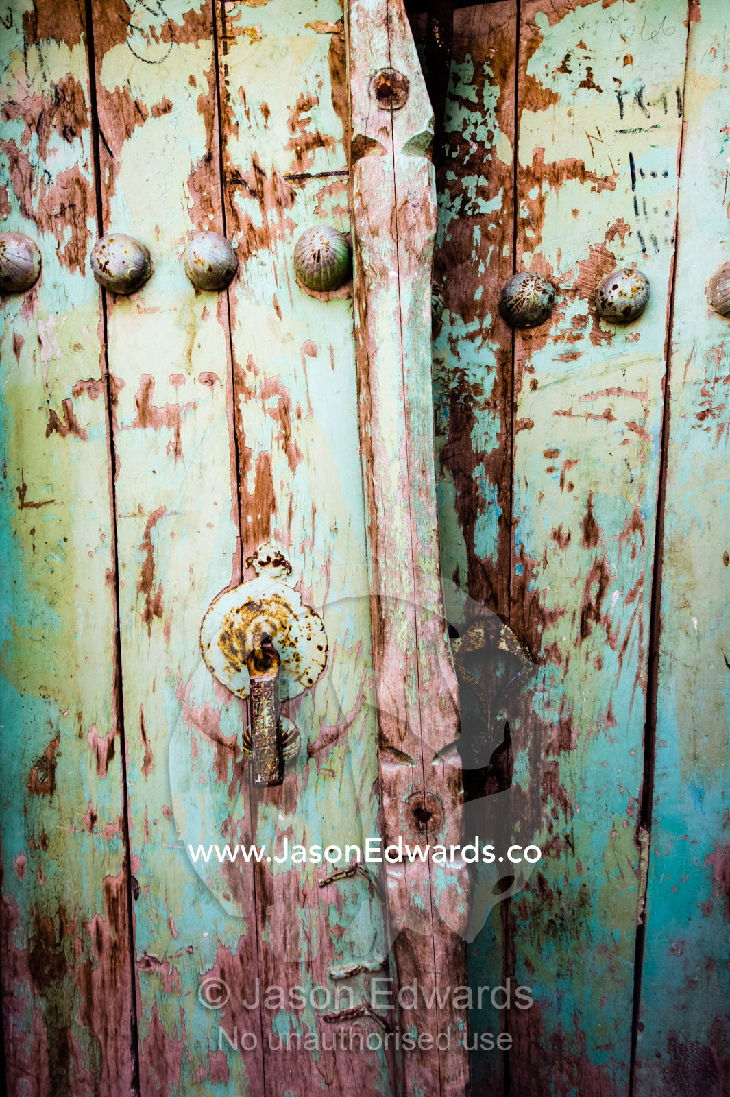 Peeling paint on a partially opened weathered wooden door. Niasar, Neyasar District, Kashan County, Isfahan Province, Islamic Republic of Iran.