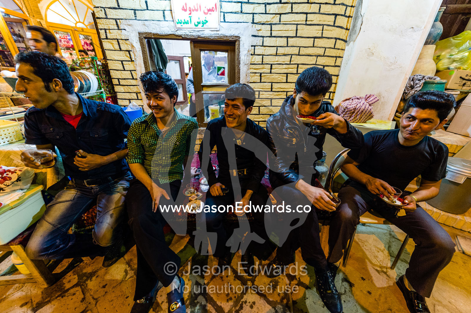 A group of friends taking a tea break from selling goods in an ancient bazaar. The Bazaar of Kashan, Kashan, Isfahan, Islamic Republic of Iran.