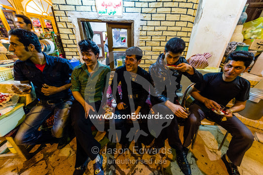 A group of friends taking a tea break from selling goods in an ancient bazaar. The Bazaar of Kashan, Kashan, Isfahan, Islamic Republic of Iran.