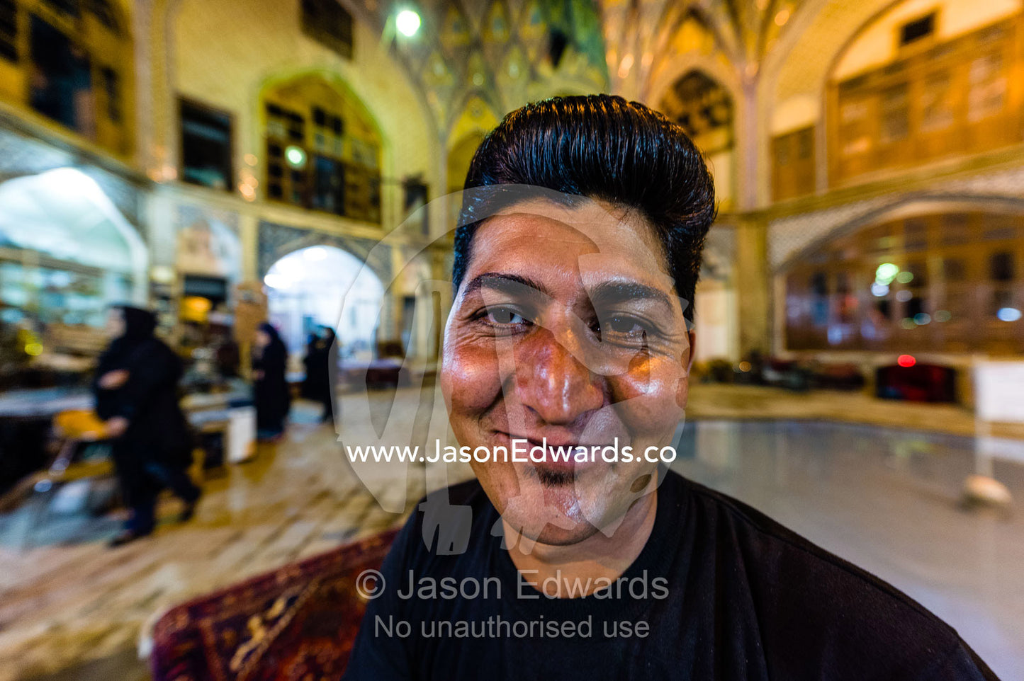 A smiling young man with a funky groomed hairstyle in an ancient bazaar. The Bazaar of Kashan, Kashan, Isfahan, Islamic Republic of Iran.