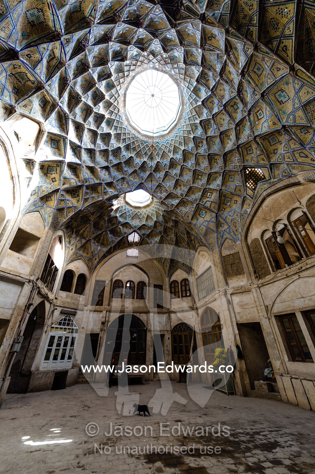 A black cat walks beneath the Dome of Timche ye Amin Al Dowleh Caravanserai an ancient Bazaar. The Bazaar of Kashan, Kashan, Isfahan, Islamic Republic of Iran.