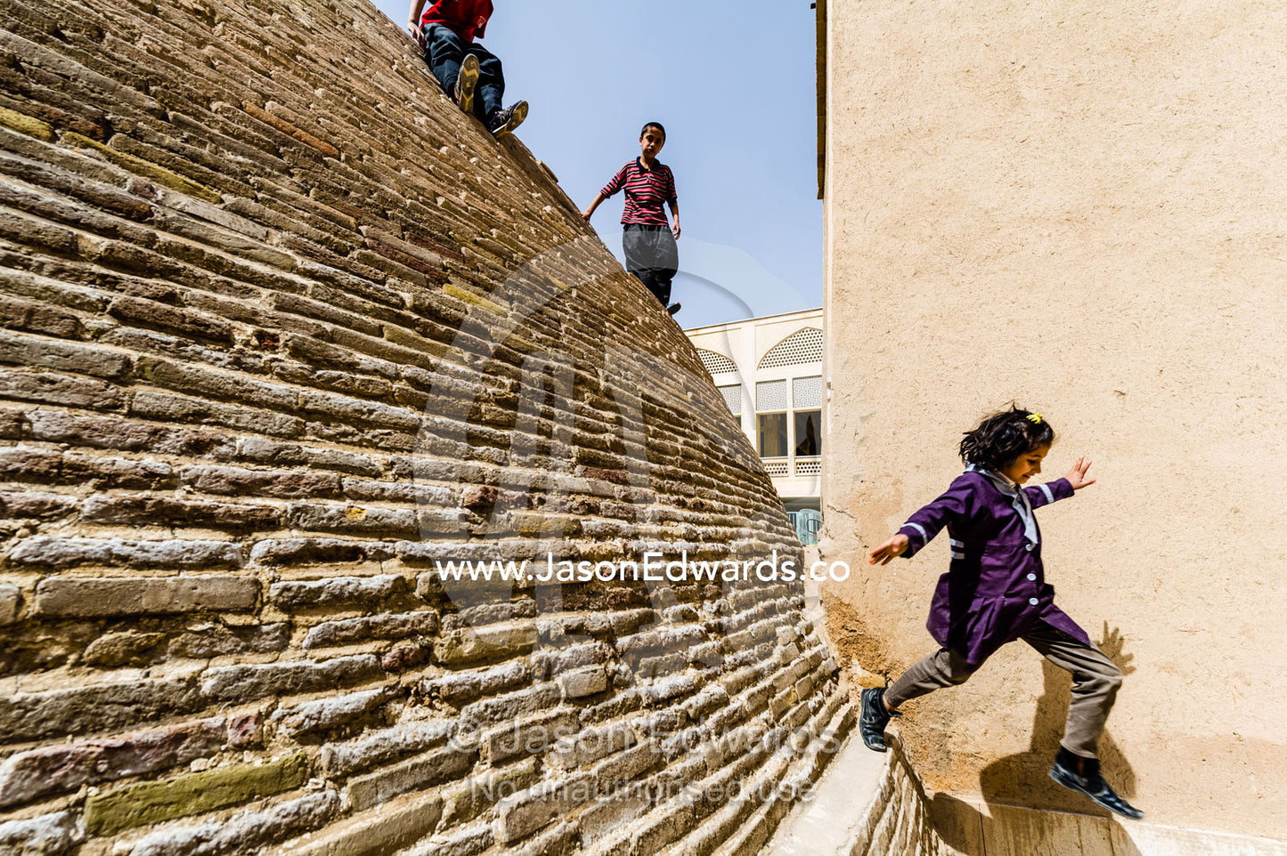 A girl jumps from the steep sides of an ancient handmade brick cistern containing town water. Kashan, Isfahan, Islamic Republic of Iran.
