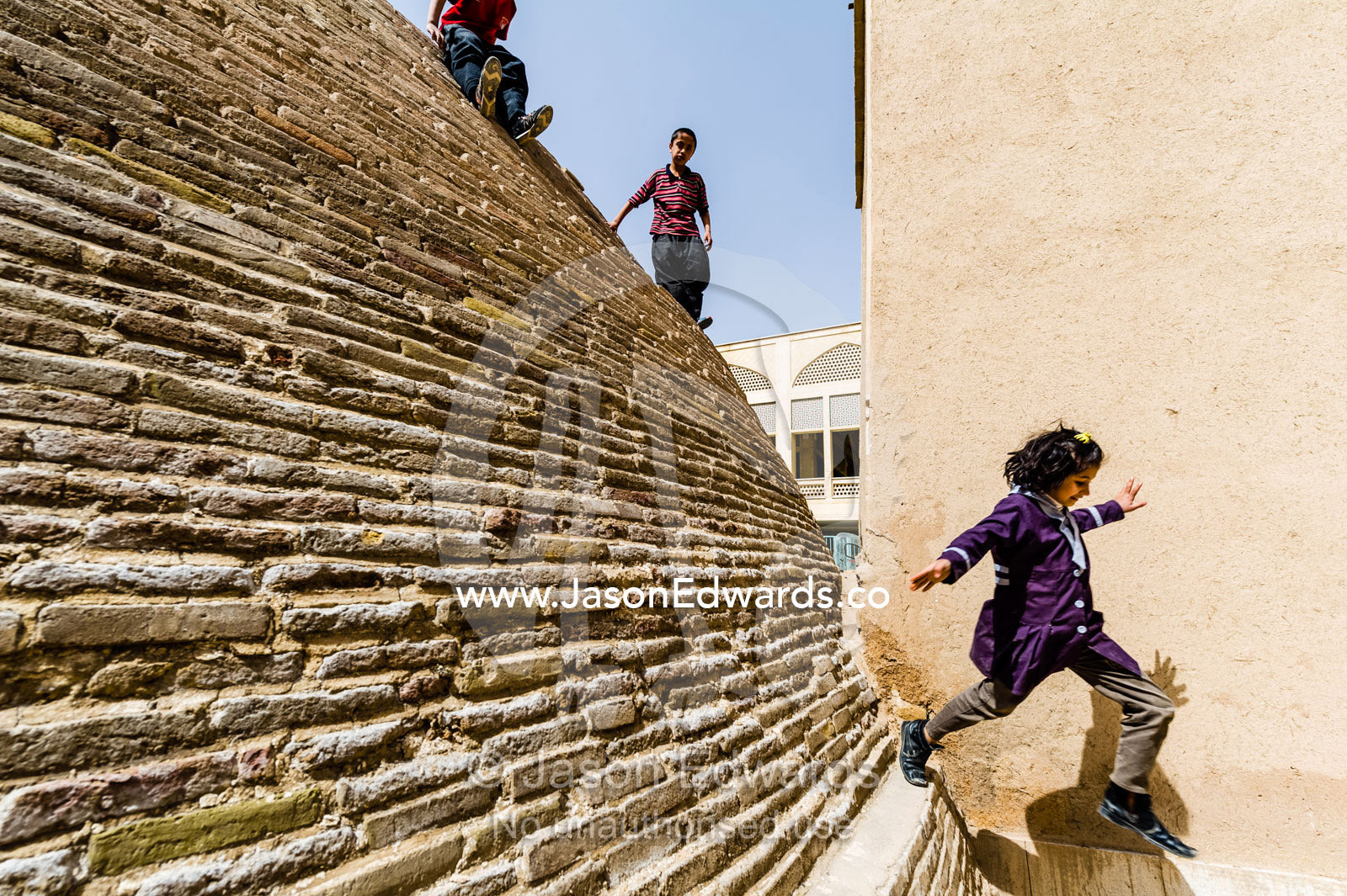A girl jumps from the steep sides of an ancient handmade brick cistern containing town water. Kashan, Isfahan, Islamic Republic of Iran.