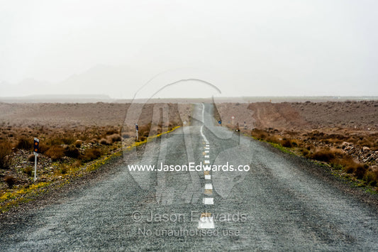 A bitumen road crosses a barren desert plain. Barzrud Rural District, Natanz County, Isfahan Province, Islamic Republic of Iran.