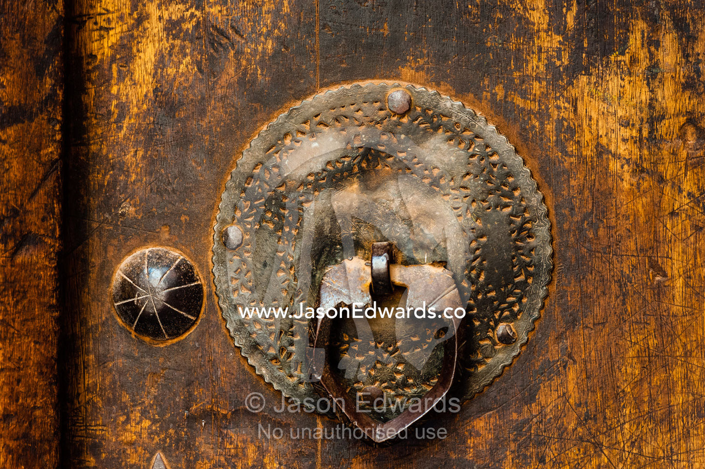 An antique brass door tapper on a wooden door in old village. Abyaneh Village, Abyaneh, Barzrud Rural District, Natanz County, Isfahan Province, Islamic Republic of Iran.