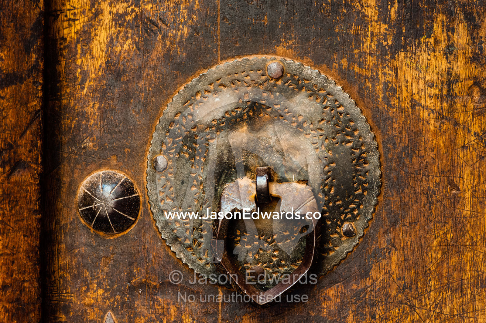 An antique brass door tapper on a wooden door in old village. Abyaneh Village, Abyaneh, Barzrud Rural District, Natanz County, Isfahan Province, Islamic Republic of Iran.