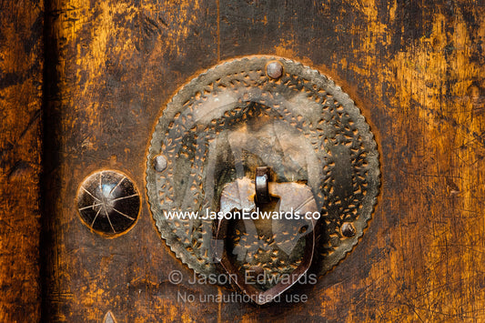 An antique brass door tapper on a wooden door in old village. Abyaneh Village, Abyaneh, Barzrud Rural District, Natanz County, Isfahan Province, Islamic Republic of Iran.