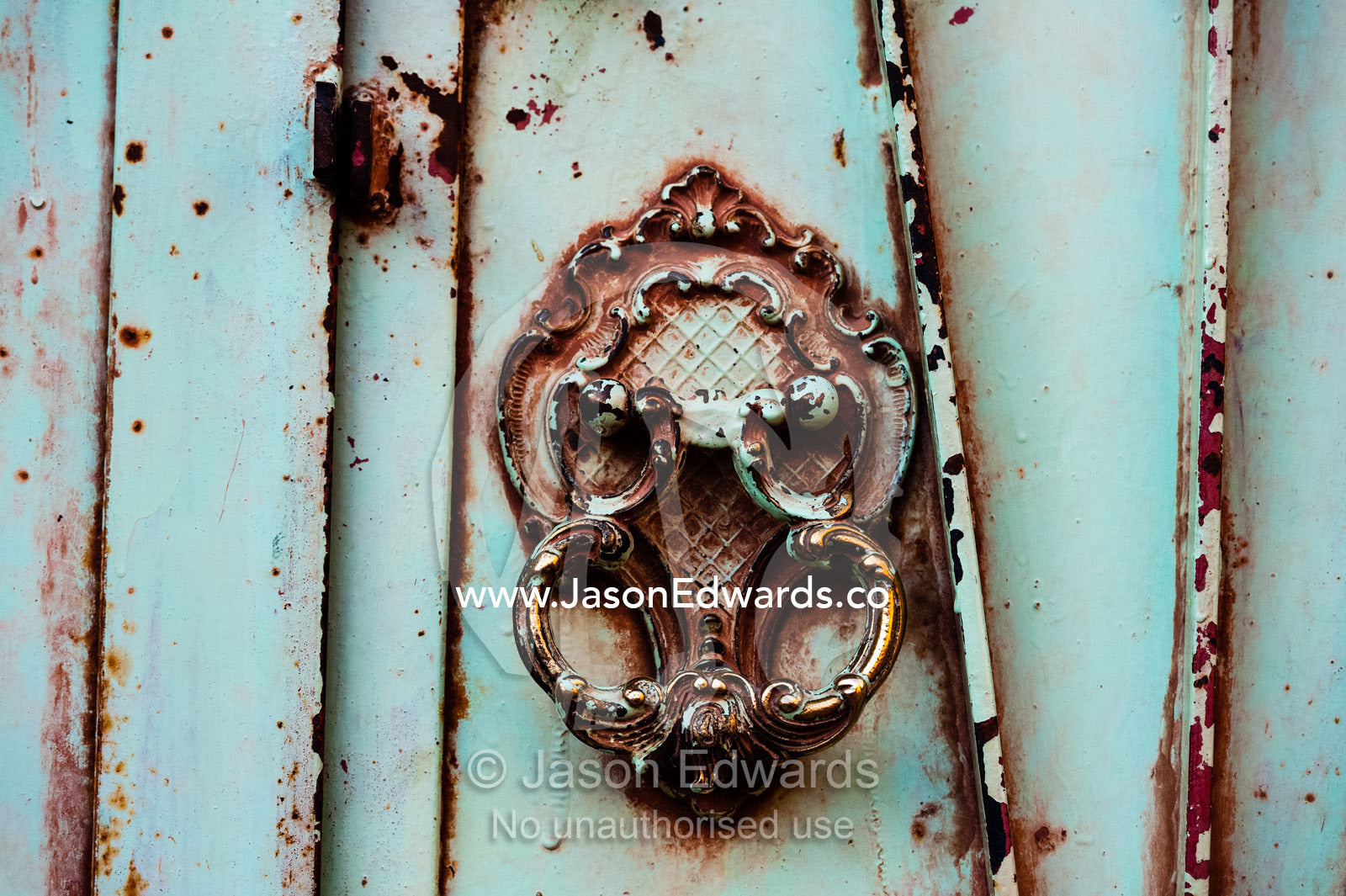 An antique door tapper on a peeling steel door in old village. Abyaneh Village, Abyaneh, Barzrud Rural District, Natanz County, Isfahan Province, Islamic Republic of Iran.