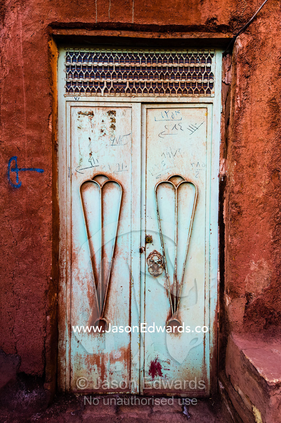 A pair of peeling steel doors in a red ochre house wall. Abyaneh Village, Abyaneh, Barzrud Rural District, Natanz County, Isfahan Province, Islamic Republic of Iran.