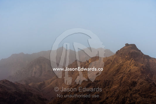 Sunset descends over the misty rugged peaks of desert mountains. Abyaneh, Barzrud Rural District, Natanz County, Isfahan Province, Islamic Republic of Iran.