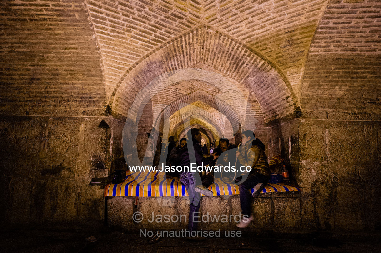 A family gathers beneath the vaulted ceiling of the khaju Bridge to smoke the hookah. Khaju Bridge, Isfahan, Isfahan Province, Islamic Republic of Iran.