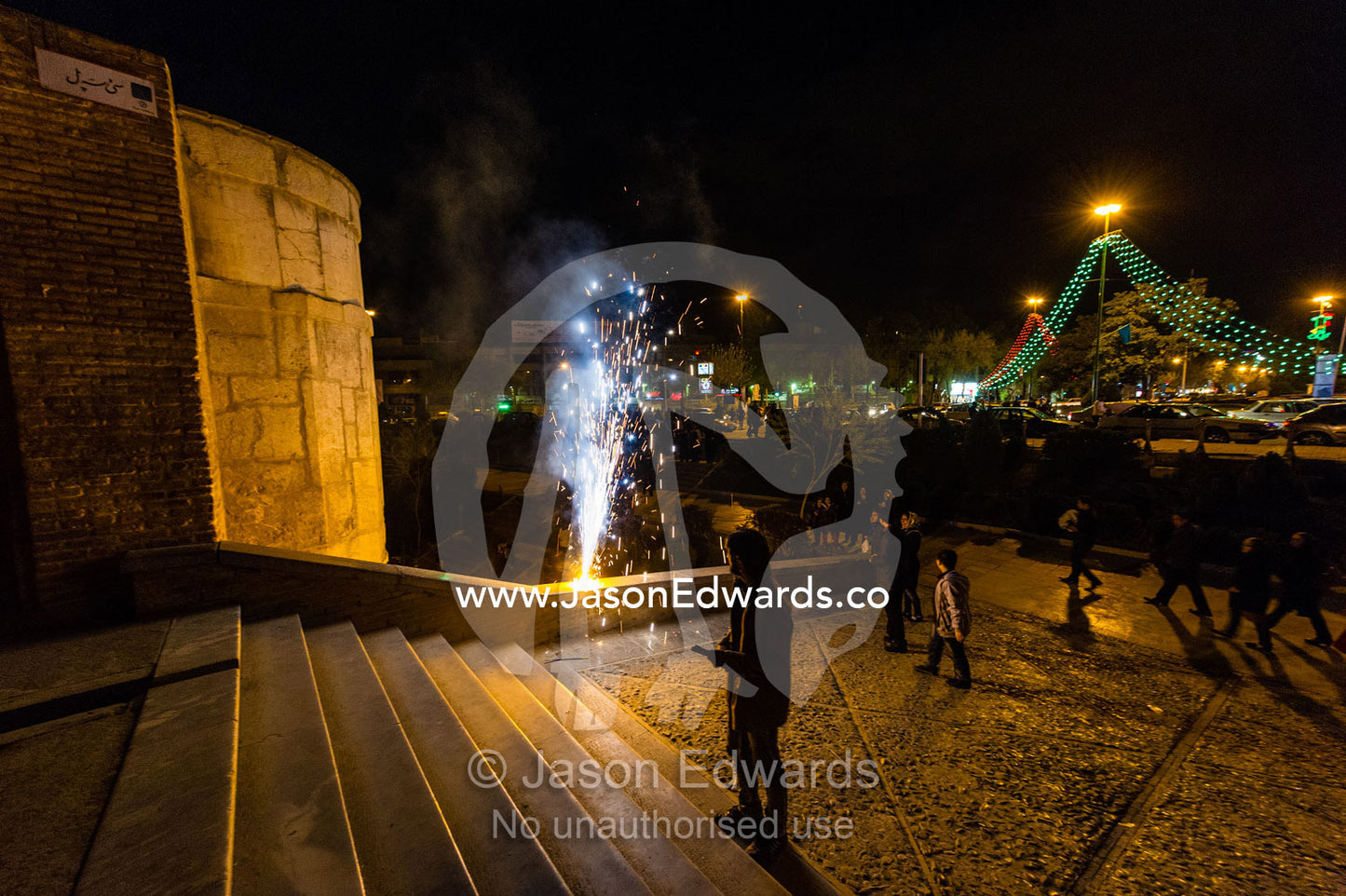 Light cascades from iwans lining the Khaju Bridge onto families and friends celebrating with fireworks during Nowruz Iranian New Year. Si-o-seh pol Bridge, Zayandeh River, Isfahan, Isfahan Province, Islamic Republic of Iran.
