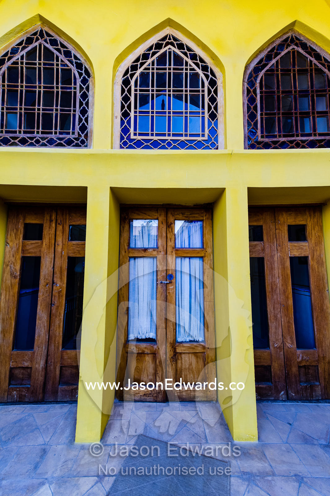 Arched pane glass windows in a canary yellow wall of a traditional house. Dibai house, Isfahan, Isfahan Province, Islamic Republic of Iran.