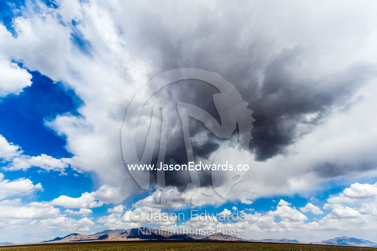 A large storm cloud sweeps in from the desert over a mountain plain. Road to Nain, Nain County, Isfahan Province, Iran.