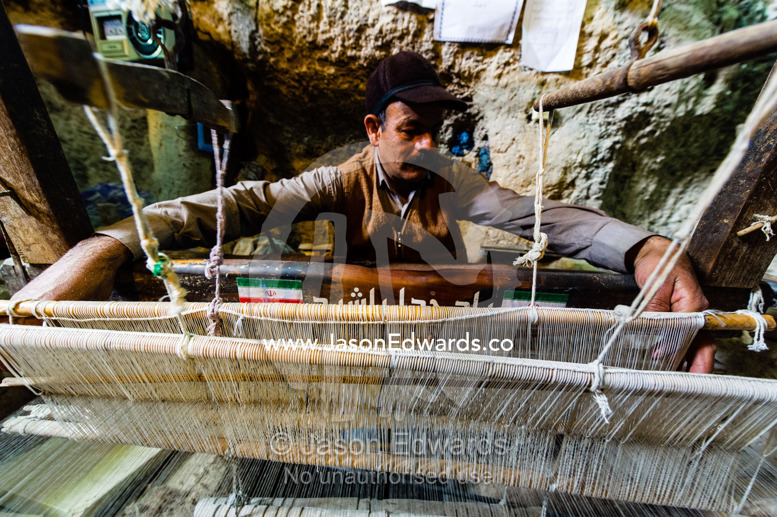 A man practicing traditional cloak weaving on an antique loom in a cave in the desert. Nain, Nain County, Isfahan Province, Iran.