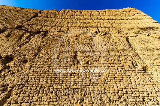 The imposing mud brick wall of an ancient fortress towers over the desert. Narin Castle, Meybod, Meybod County, Yazd Province, Islamic Republic of Iran.