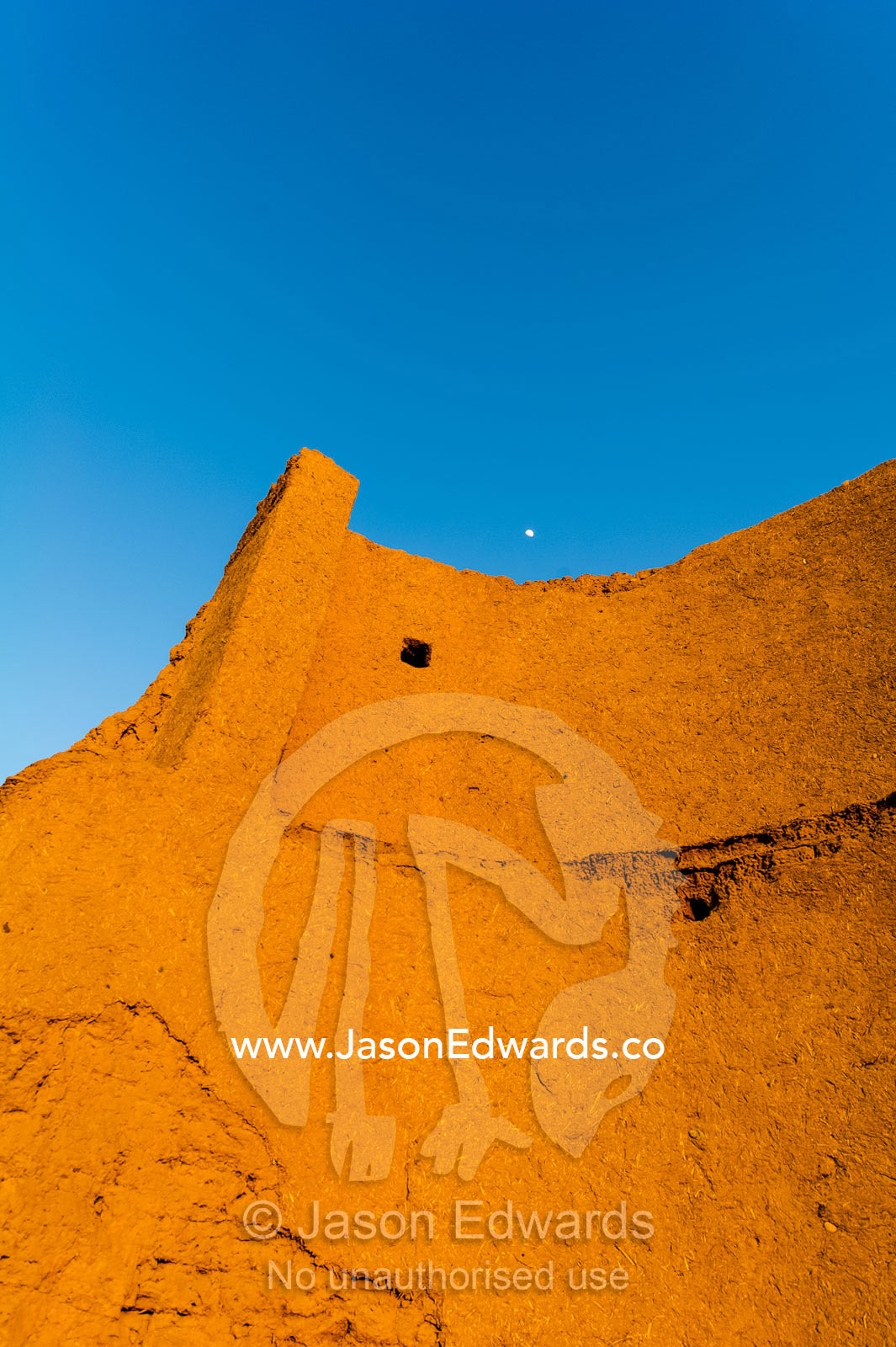 The imposing mud brick wall of an ancient fortress towers over the desert. Narin Castle, Meybod, Meybod County, Yazd Province, Islamic Republic of Iran.