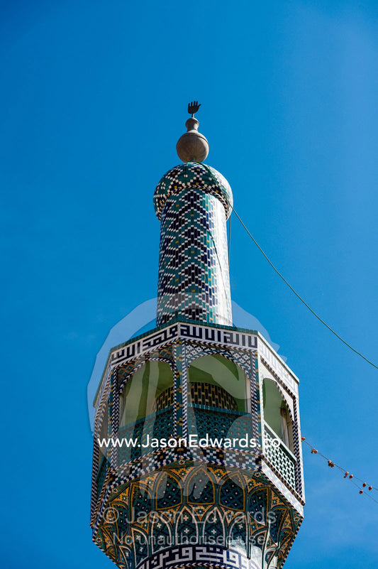 The top of a mosque minaret against a blue sky. Yazd, Yazd Province, Islamic Republic of Iran.