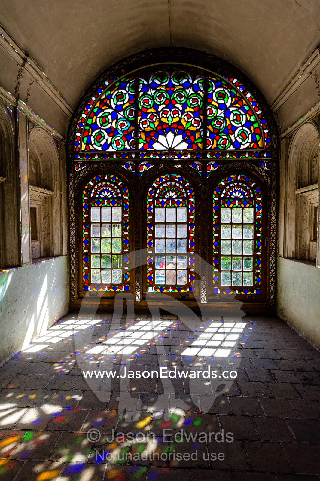 Sunlight pours through colourful stained glass windows lighting the interior of the water museum. Yazd Water Museum, Yazd, Yazd Province, Islamic Republic of Iran.